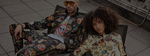 Two people in bold, retro-inspired clothing with graphic prints and vibrant patterns, lounging outdoors.